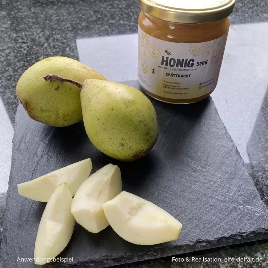 Spättracht-Honig ganzen Birnen und geviertelten Birnen auf einer Schieferplatte dekoriert