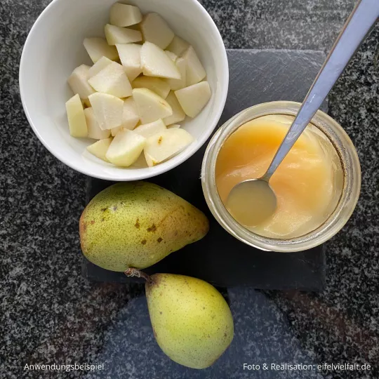 Birnenkompott im Glas mit ganzen Birnen und Birnenstücken auf Schiefertafel dekoriert