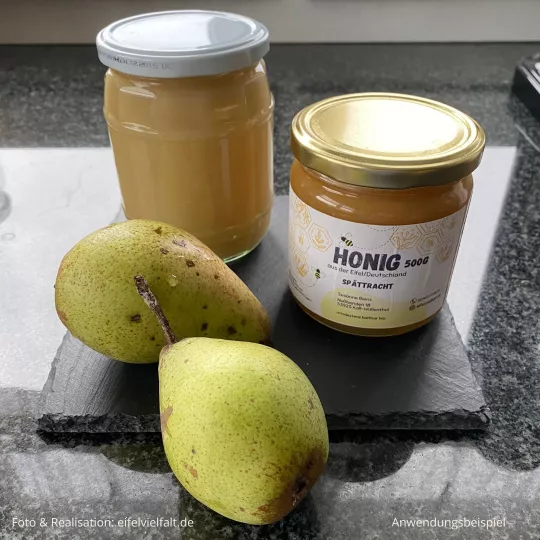 Birnenmus im Glas mit Birnen und Honig auf Schiefertafel dekoriert