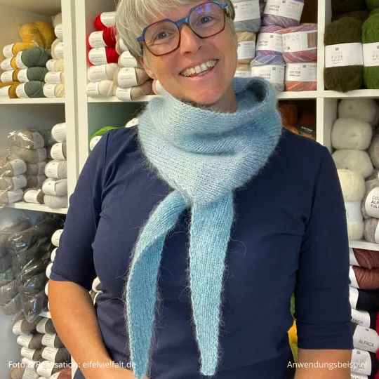 Frau trägt blauen Schal vor einem Wollregal