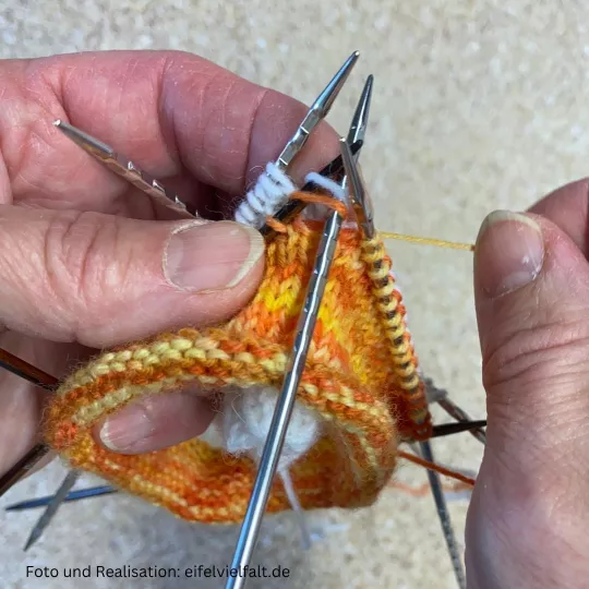 2 Bünchen werden mit Hauptfarbe gelb-orange zusammengestrickt