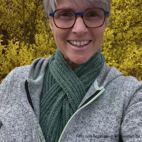 Frau rägt selbstgestrickten seegrünen Steckschal zu einer grün-melierten Jacke