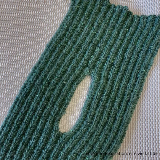 fertig gestrickter Schlitz vom Steckschal Kermeter liegt flach auf dem Tisch