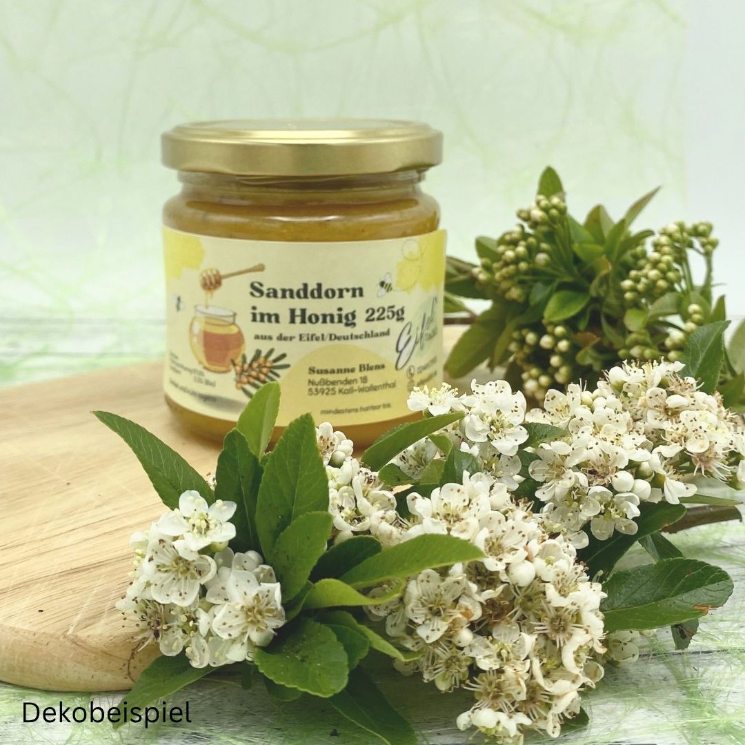 Sanddorn im Honig 225g mit Blüten und Zweigen als Dekoration auf einem Holzbrett