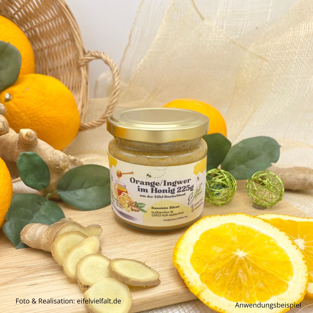 Orange Ingwer im Honig 225g Honigkreation mit fruchtiger und fein-würziger Schärfe im Glas - dekoriert mit Orangenscheiben und Ingwerscheiben auf einem Holzbrettchen
